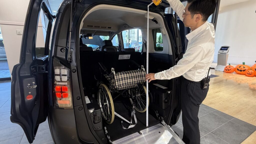 Honda Cars 東京西 さくらモール羽村店のスタッフが、FREED CROSSTAR 車いす仕様車の後部開口部の高さをメジャーで測っているところ
