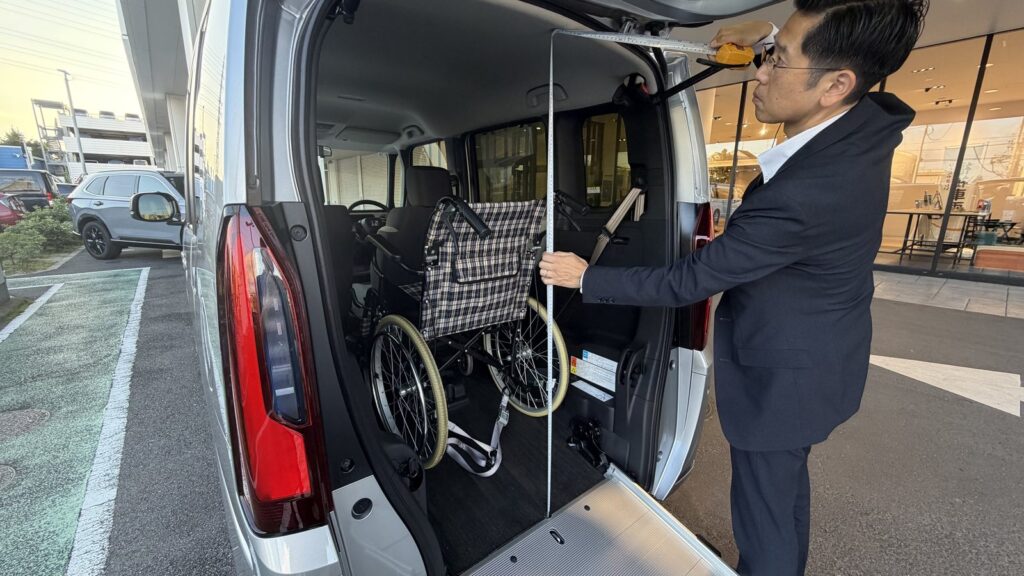 Honda Cars 東京西 さくらモール羽村店のスタッフが、N-BOX 車いす仕様車の後部開口部の高さをメジャーで測っているところ